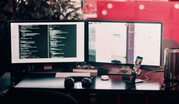 two black computer monitors on black table