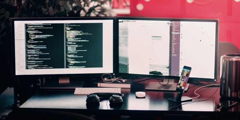 two black computer monitors on black table